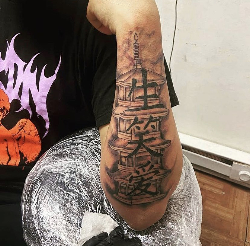 Chinese character lettering and pagoda tattoo on the forearm