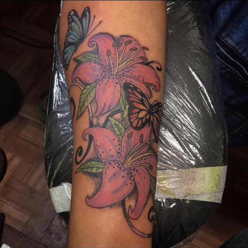 Color lily and butterfly tattoo on the forearm