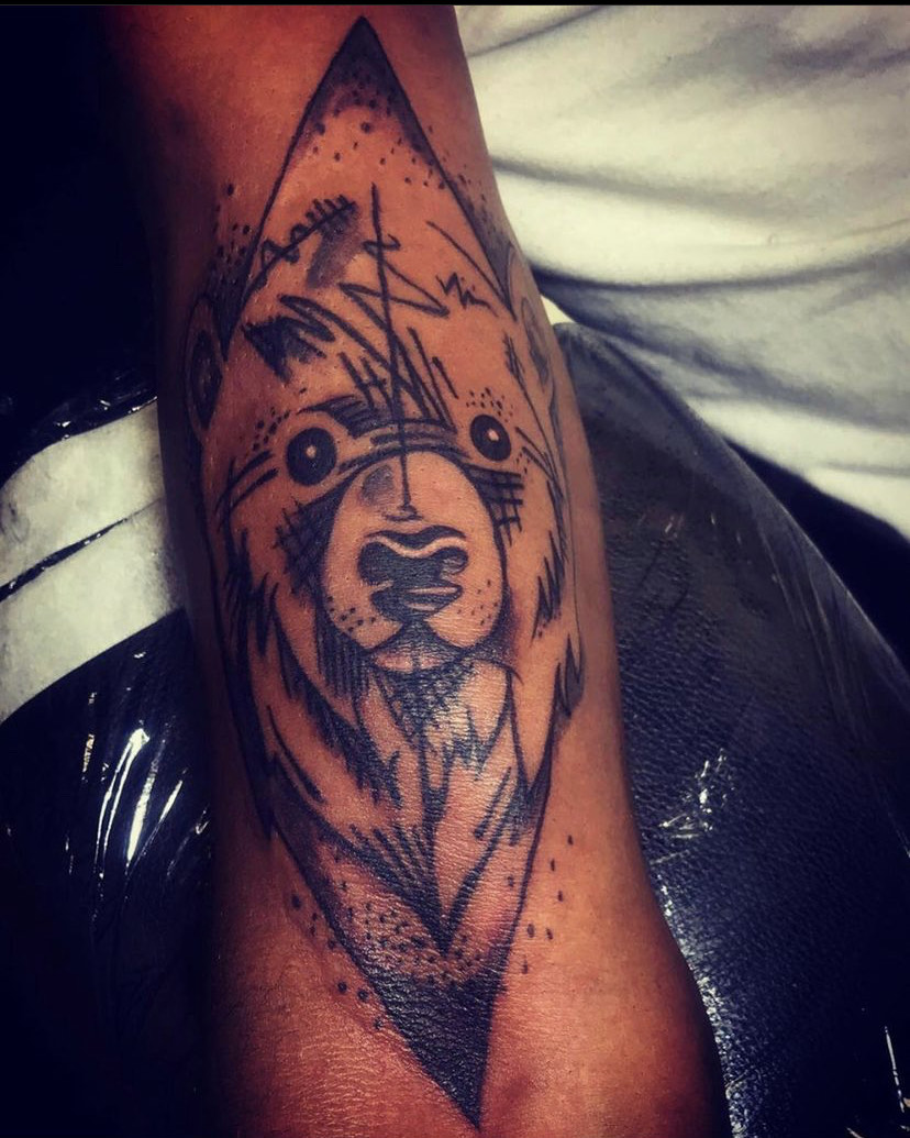 Sketch-style geometric bear tattoo on the forearm