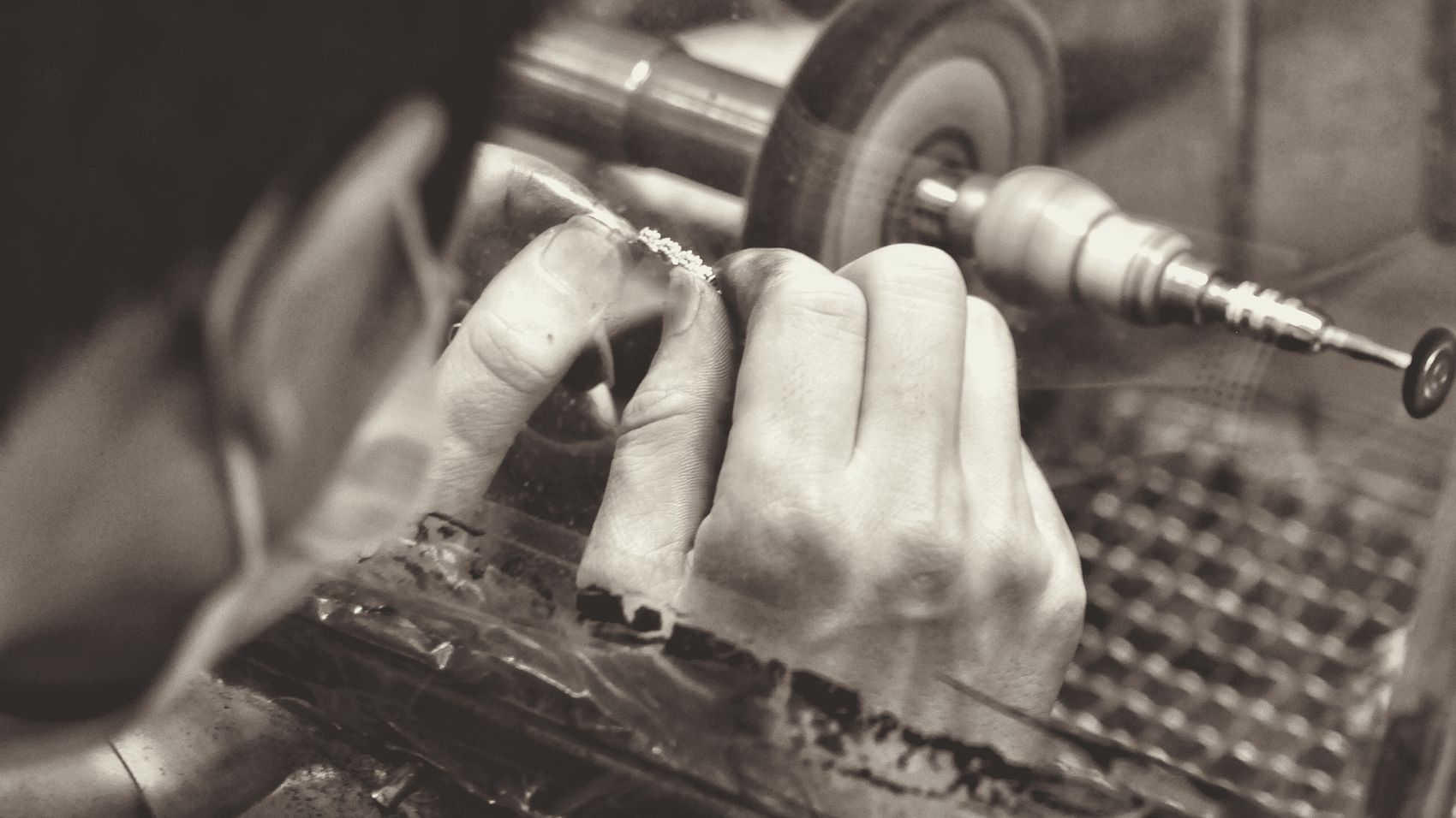 A jeweler's hands finishing a ring at the workbench