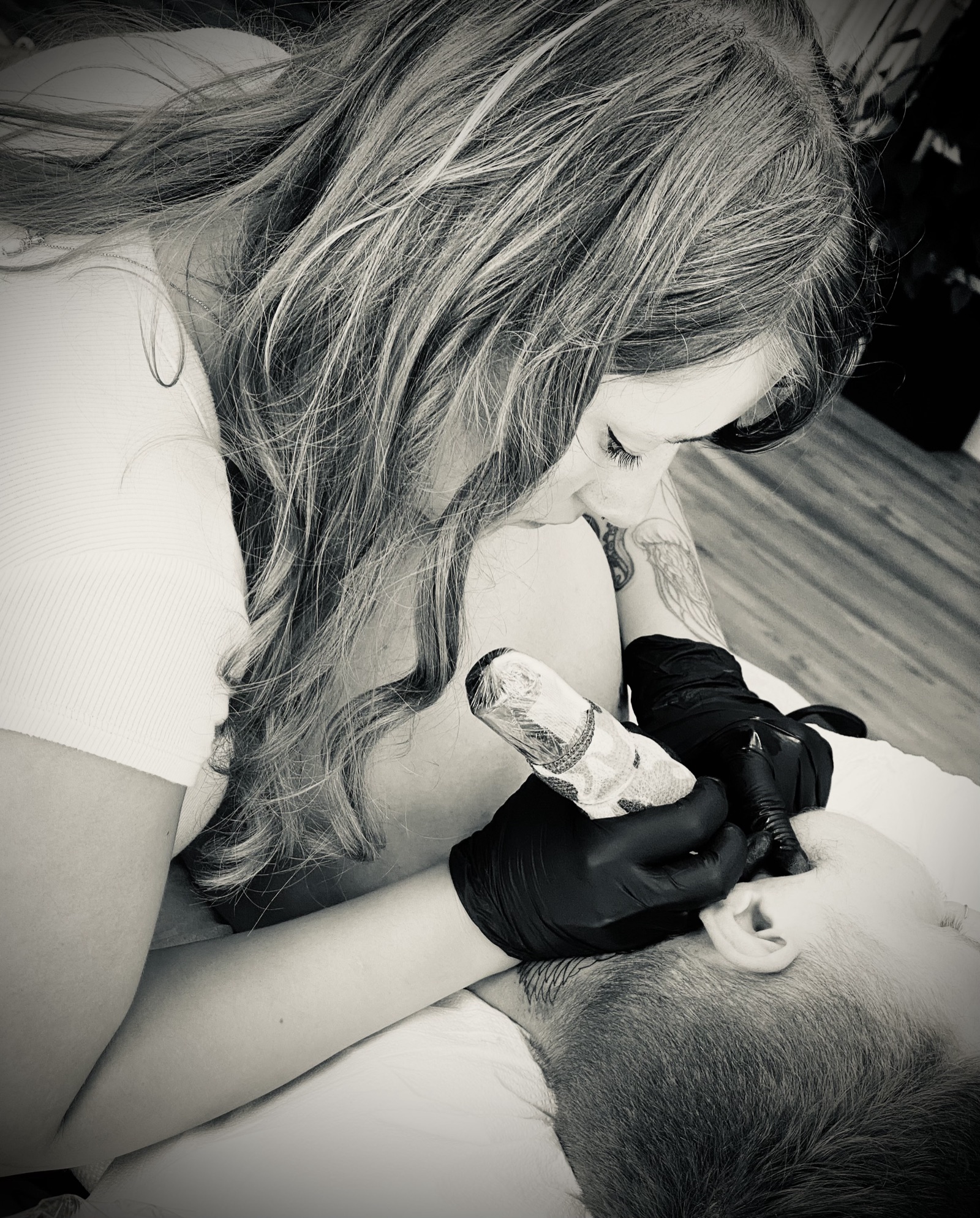Lauren tattooing a client up close, black and white