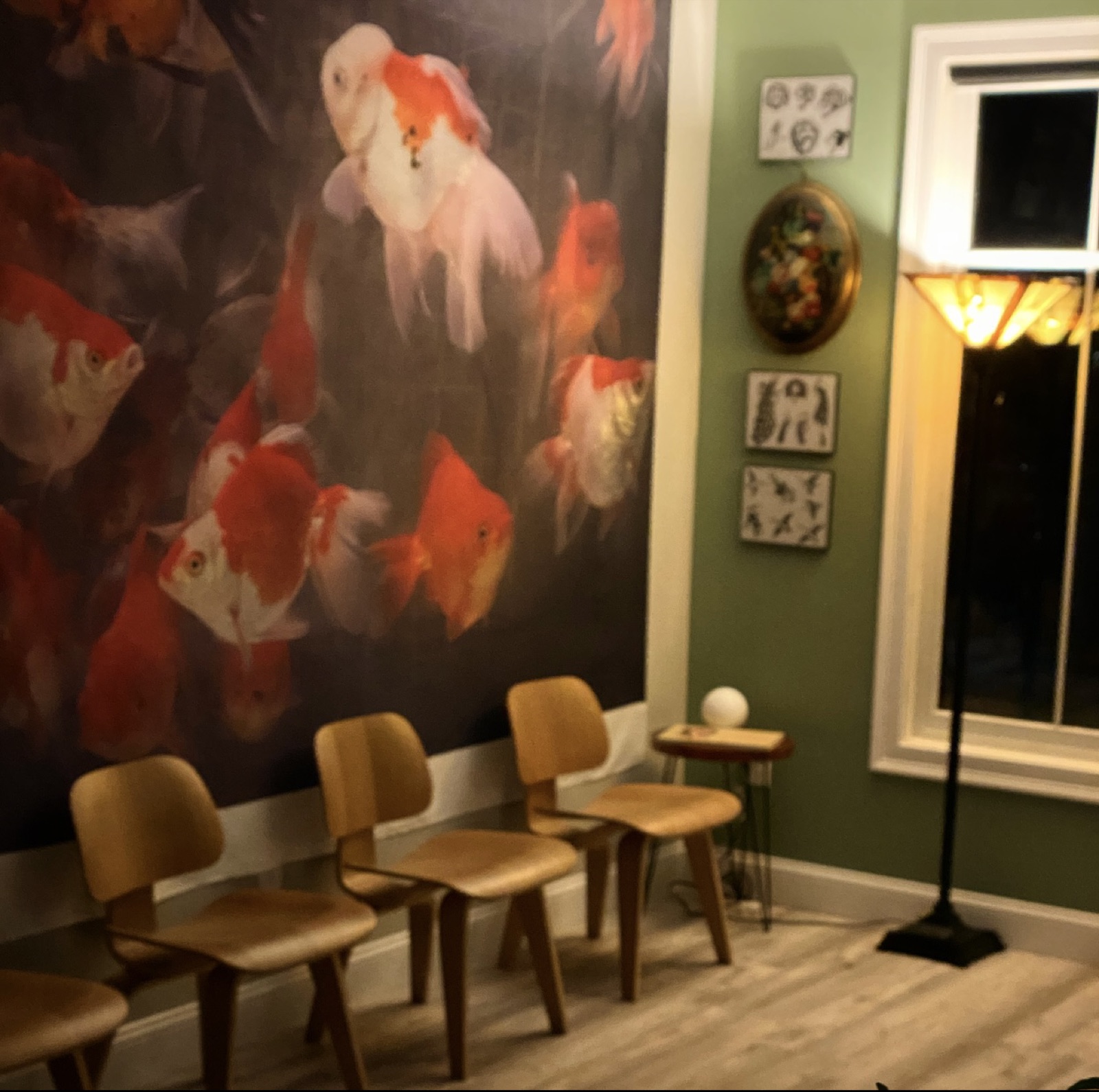 Waiting area with a large goldfish mural and mid-century wooden chairs