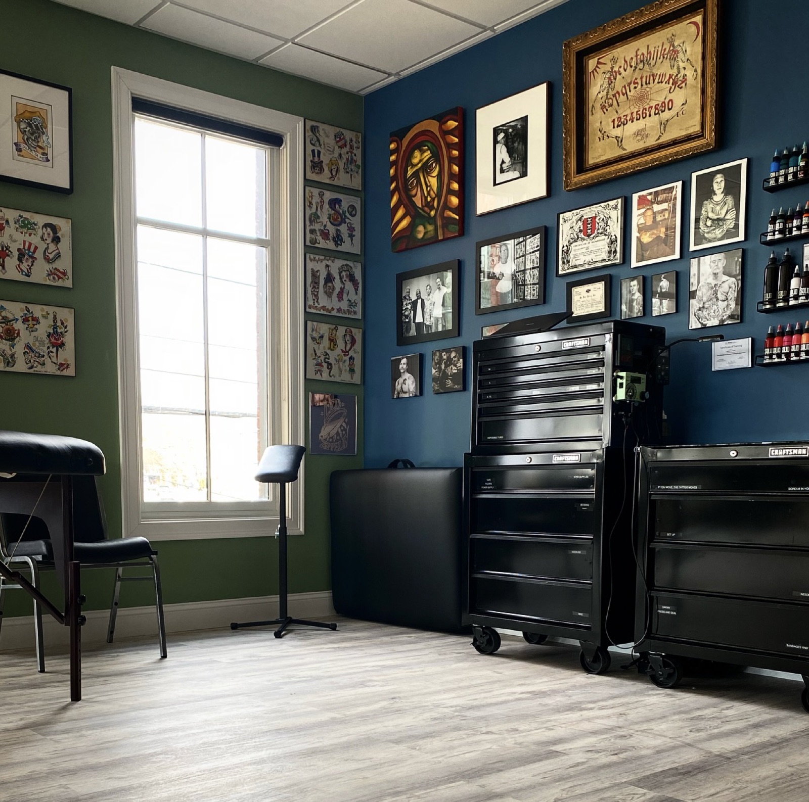 Private tattoo station with deep blue walls and rows of framed flash art