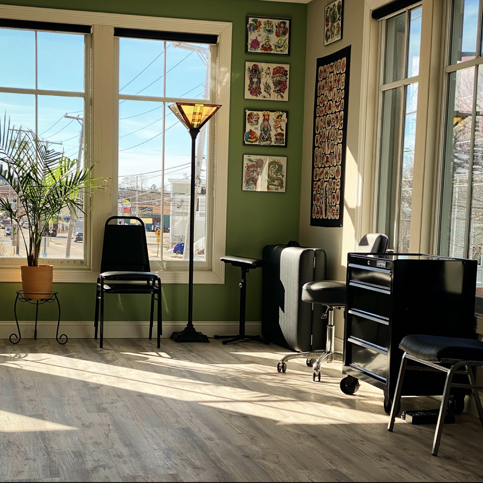 Sunlit Cosmic Sea Tattoo studio with traditional flash art on green walls and big street-facing windows