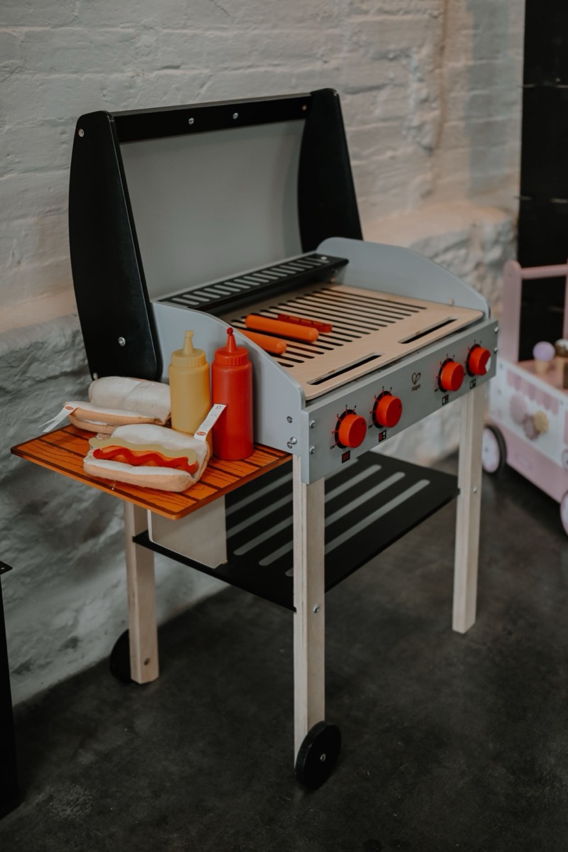 A wooden play grill with pretend food