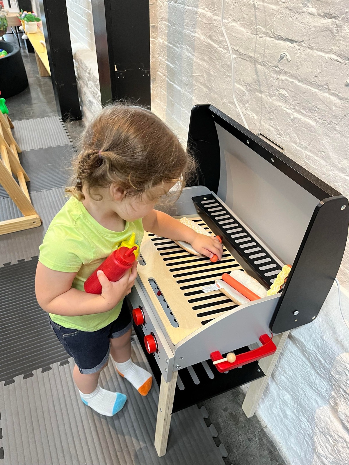 A toddler playing at the wooden play kitchen