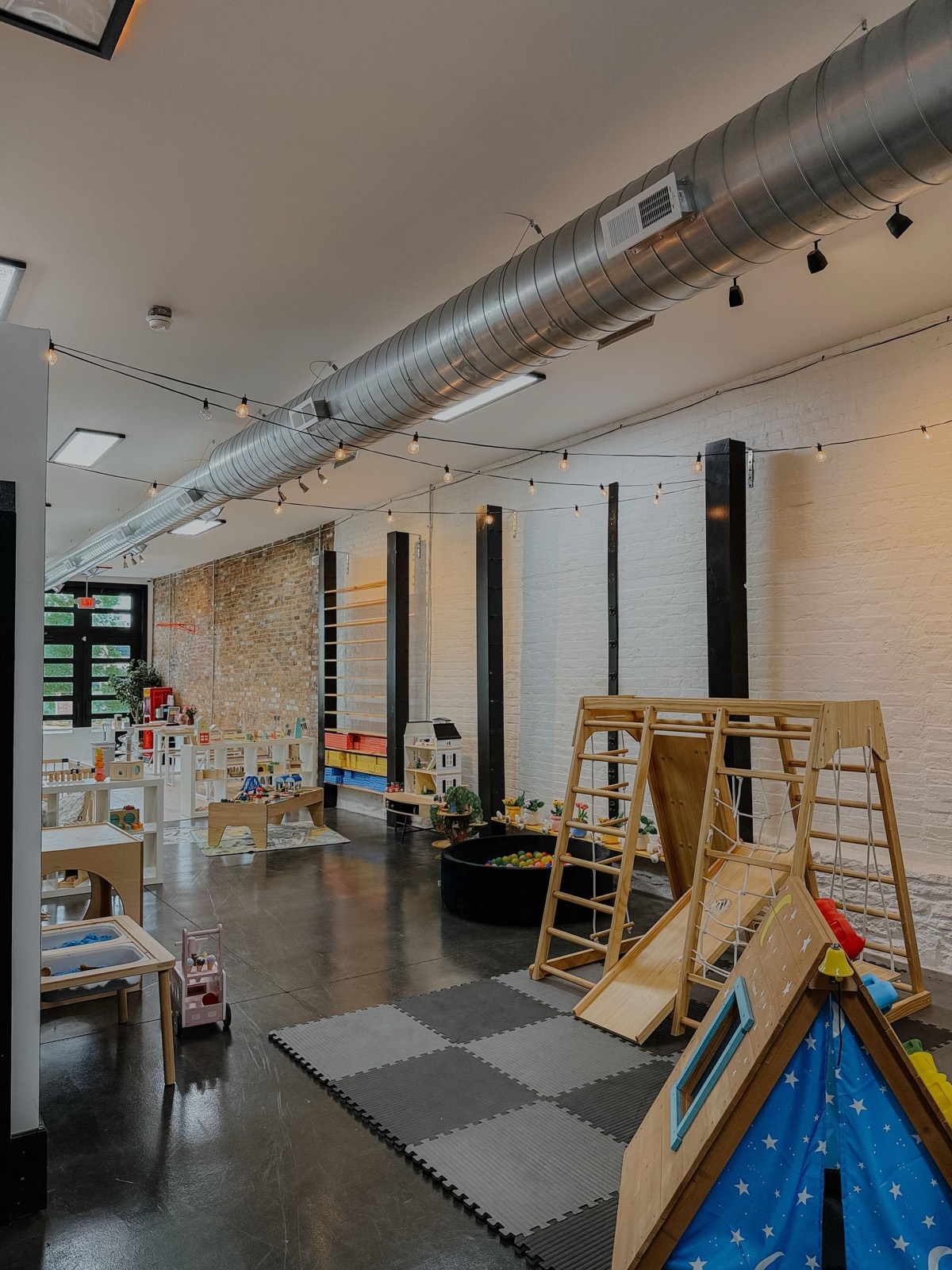 The warm, string-lit play room with wooden climbers